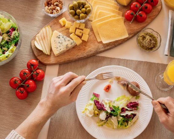 Overhead view of a cheese platter with fresh salad and juice, perfect for a gourmet lunch setting.